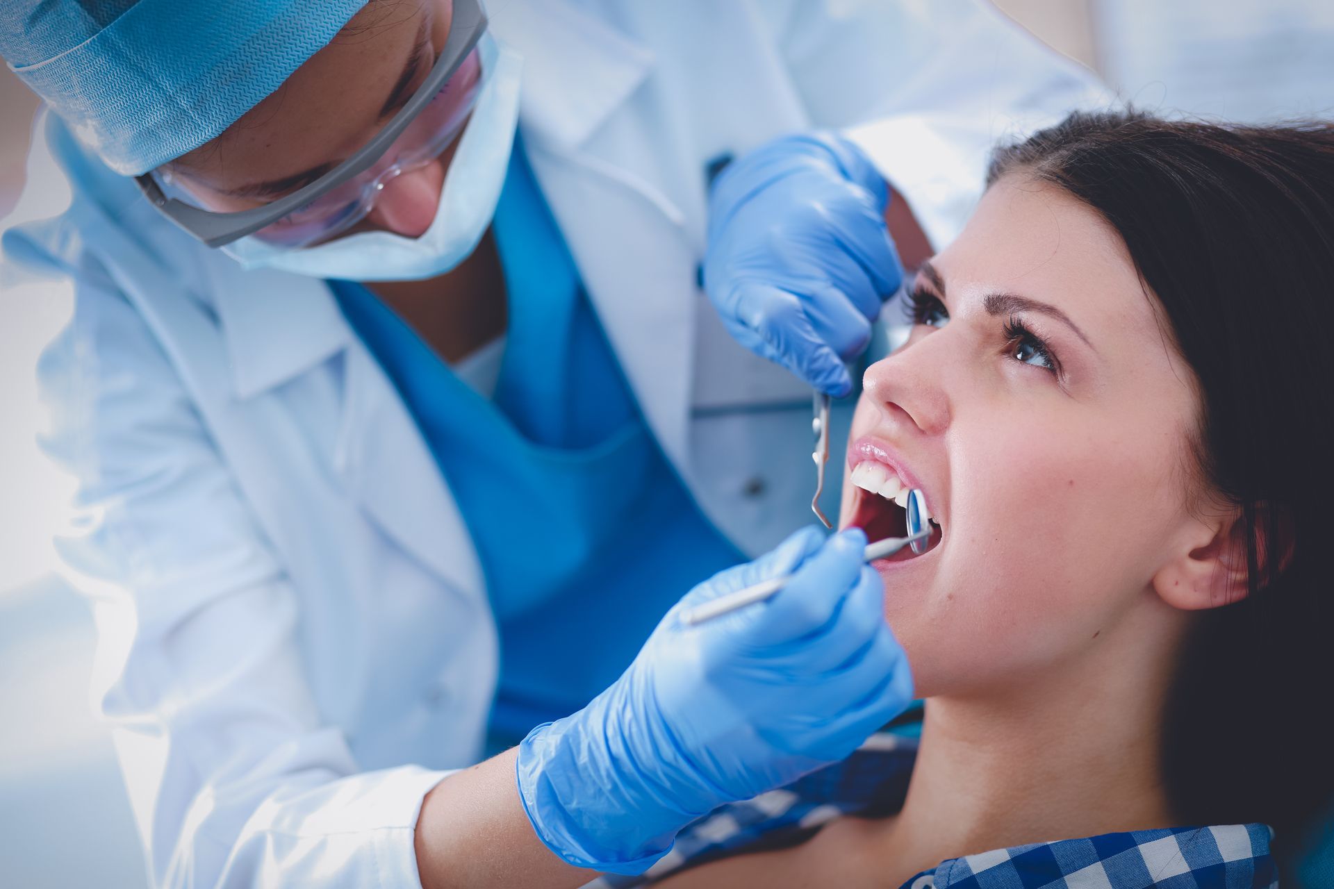 A dentist is examining a woman 's teeth in a dental office.