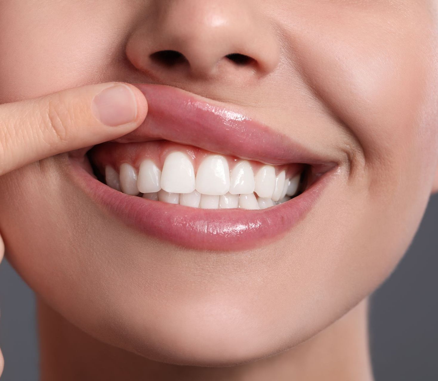 A close up of a woman 's mouth with her hand on her teeth.