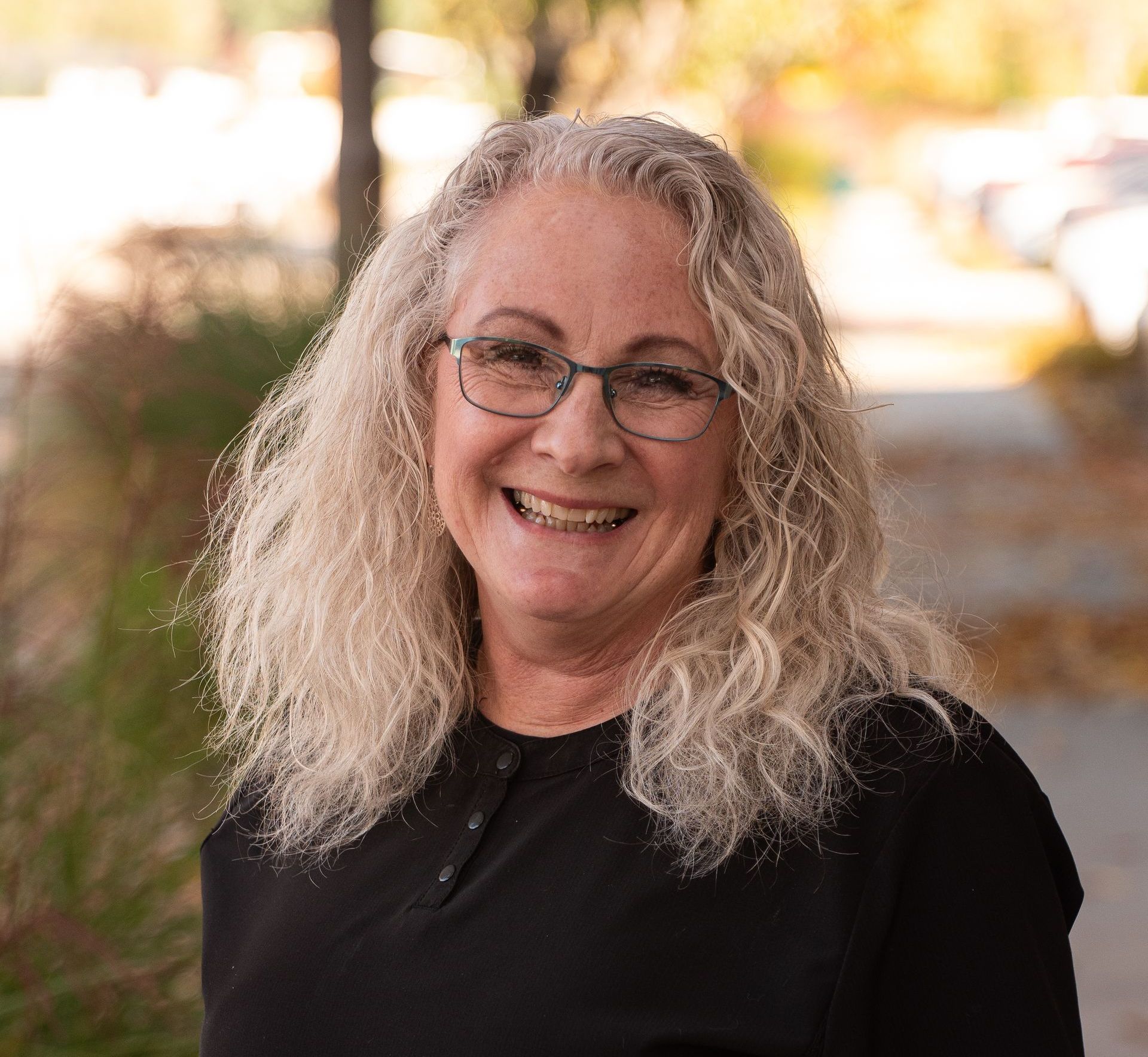 For immediate care call an emergency dentist boise id A woman wearing glasses and a black shirt is smiling for the camera.
