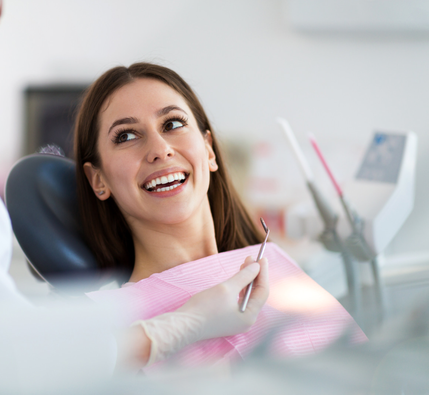 A woman is smiling while sitting in a dental chair