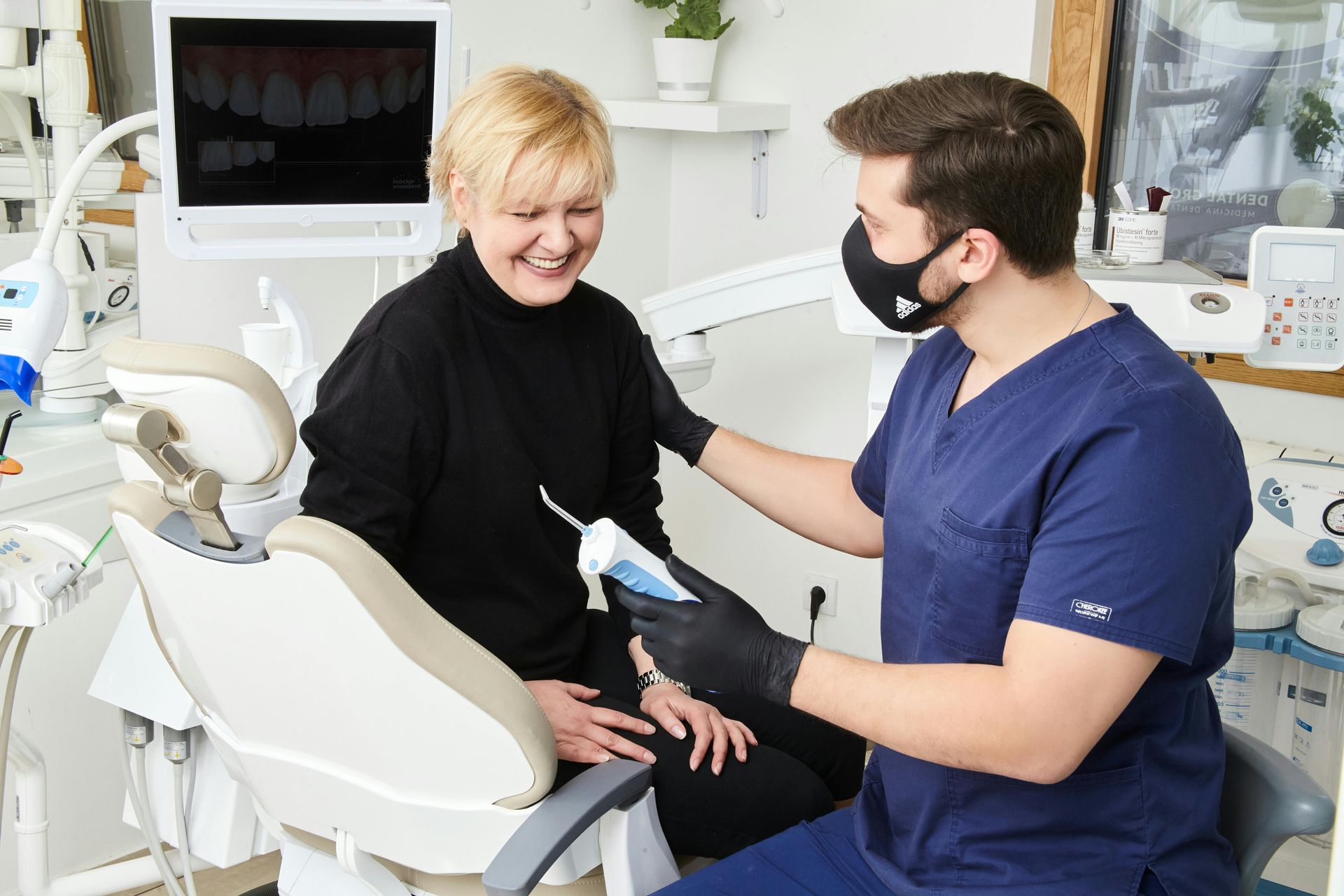 Dentist sitting down with patient showing tool and explaining details about treatment