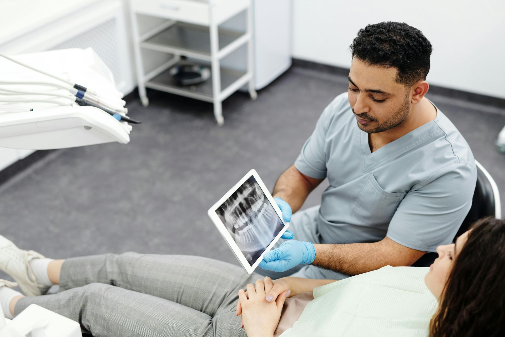 Dentist sitting with patient, showing imaging results and discussing findings