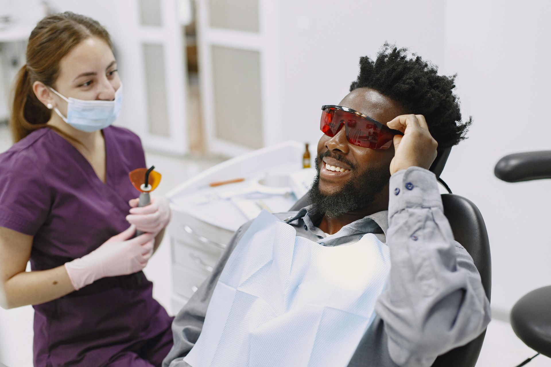 Dental assistant talking with a patient in a chair preparing for a procedure