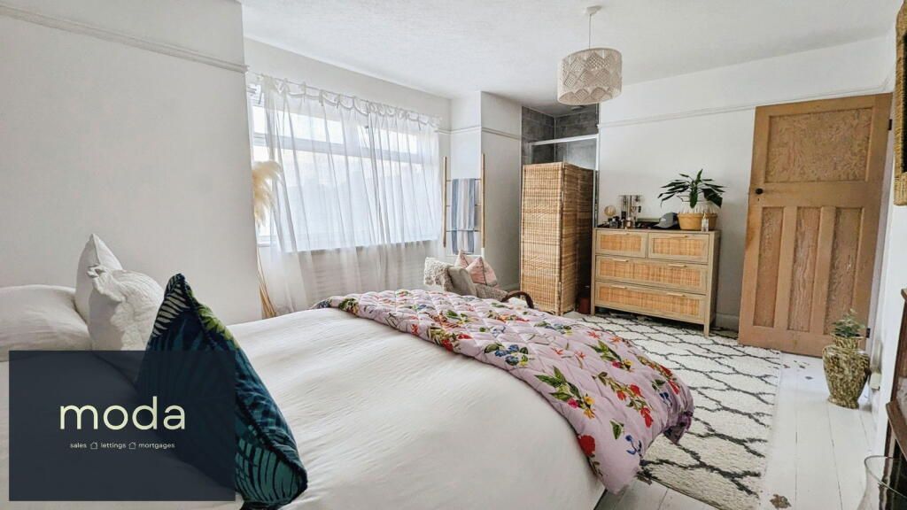 Bedroom with a bed, dresser, and rug. Bright, natural light floods the room.