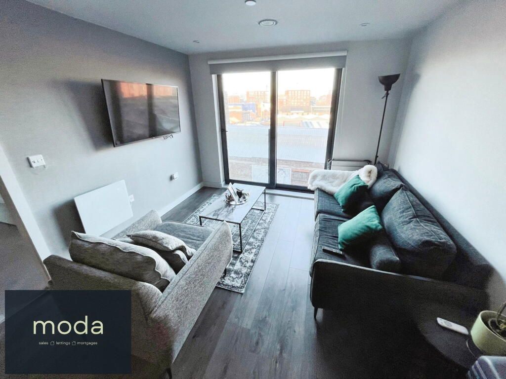Modern living room with gray walls, a dark sofa, and a large window.