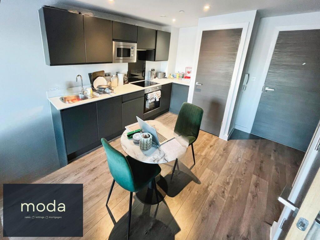 Kitchen/dining area with dark cabinets, marble table, green chairs, and wood floors.