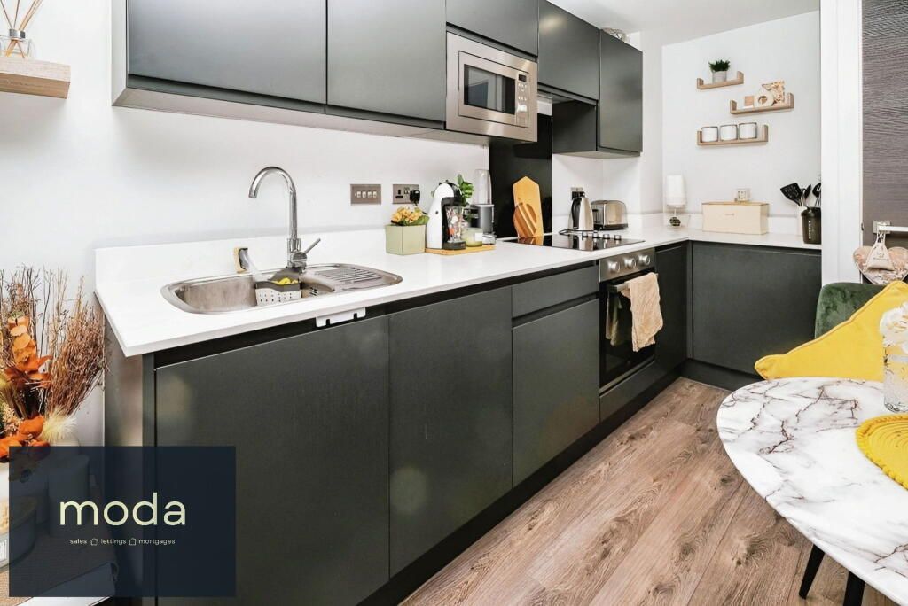 Modern kitchen with gray cabinets, white countertop, stainless steel appliances, and marble table.
