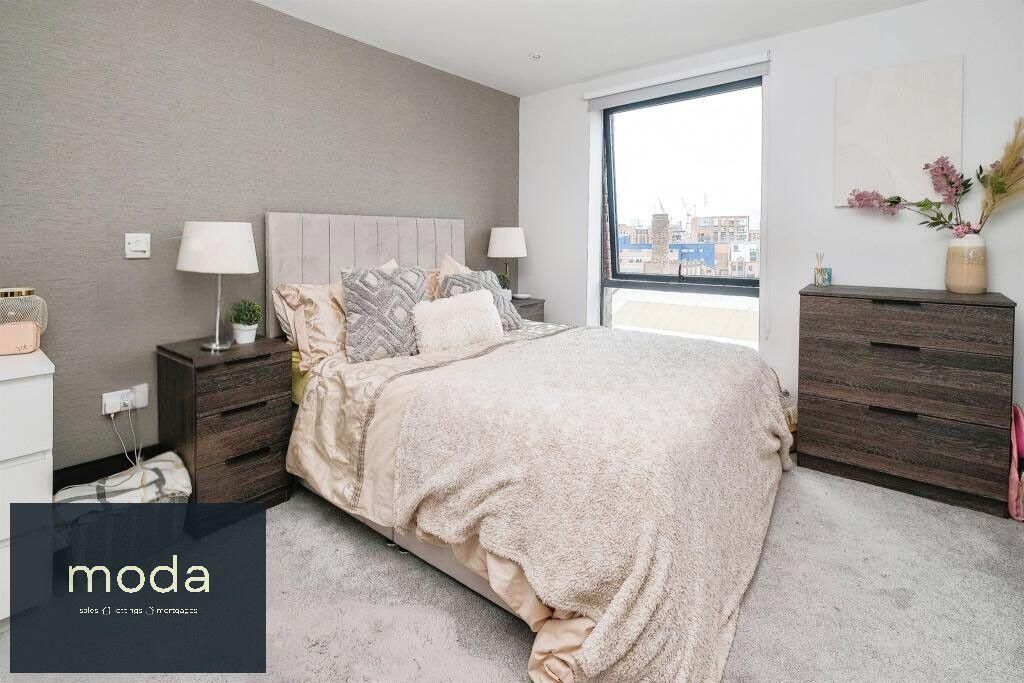 Modern bedroom with a bed, bedside tables, dresser, and window. Neutral tones.