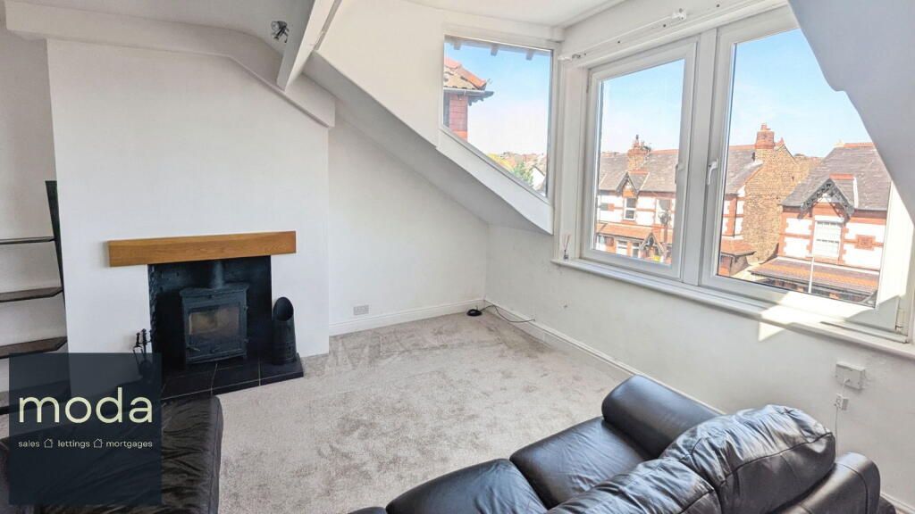 A living room with a sloped ceiling, fireplace, and a view of the exterior.