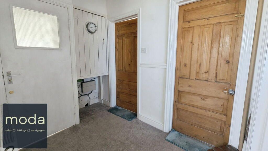 Hallway with three doors: white, light wood, and dark wood. A clock hangs on the wall.