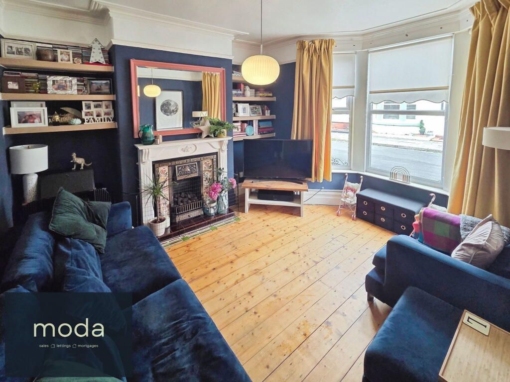 Living room with blue sofas, navy walls, fireplace, wood floor, and bay window.