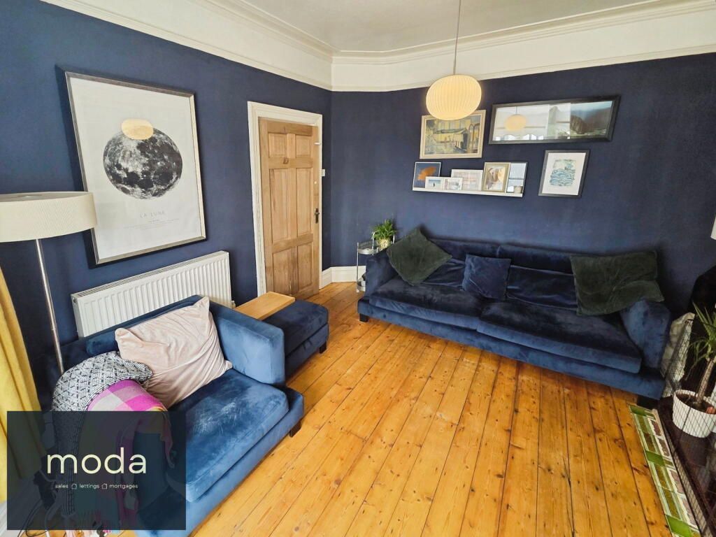 Living room with navy blue walls, wooden floor, blue sofa, and artwork.