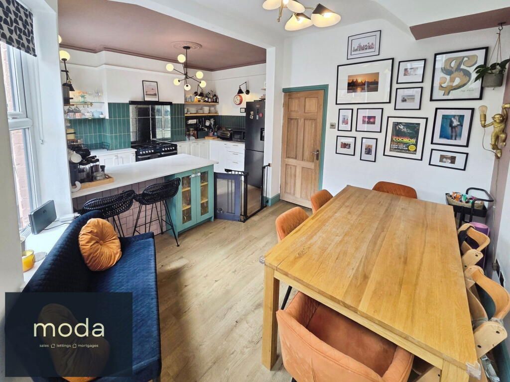 Open-concept kitchen and dining area with a wooden table, artwork, and colorful cabinets.