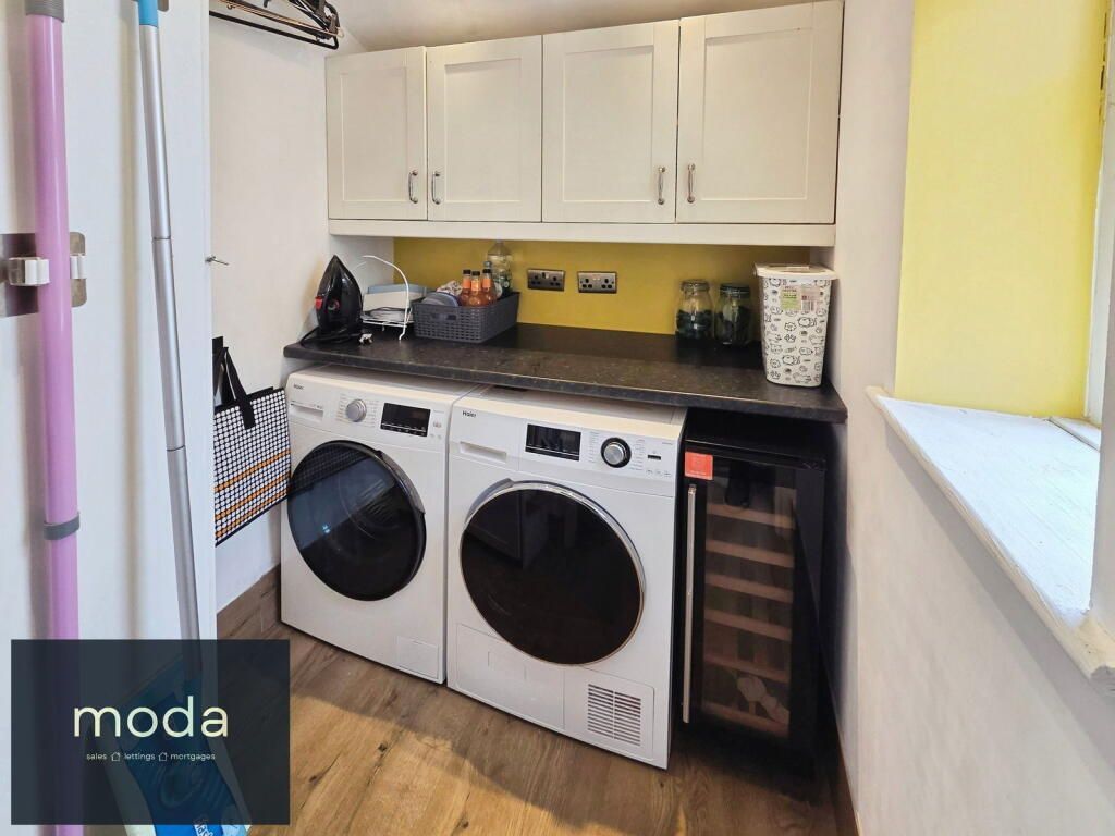 Laundry room with washer, dryer, cabinets, yellow backsplash, and wine cooler.
