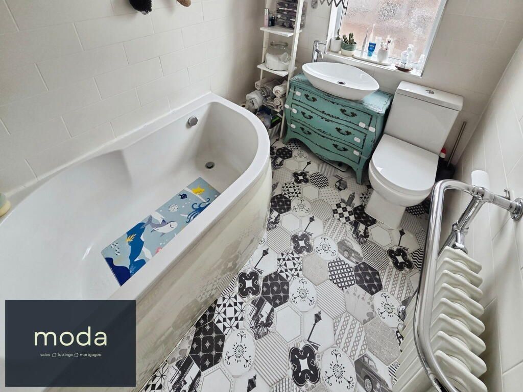 Bathroom with bathtub, toilet, sink, patterned floor.