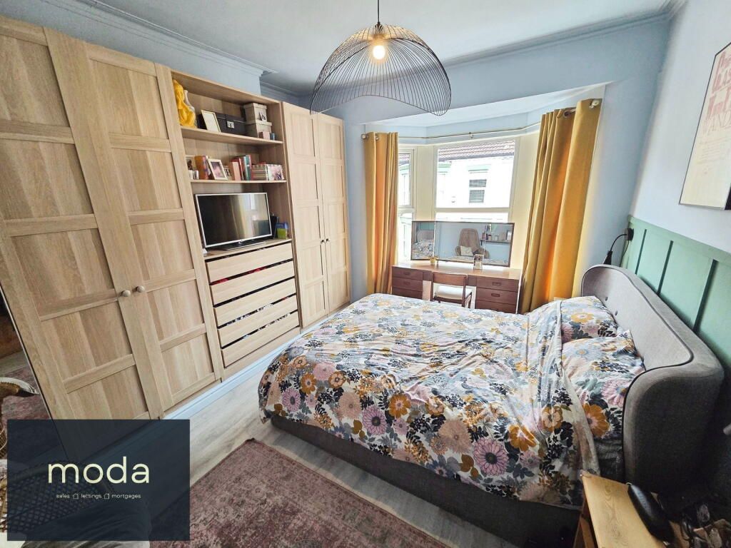 Bedroom with large wooden wardrobe, bed, desk, and window with yellow curtains.