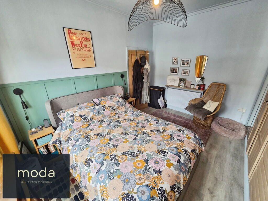 Bedroom with floral bedding, teal headboard, and a gold accent chair.