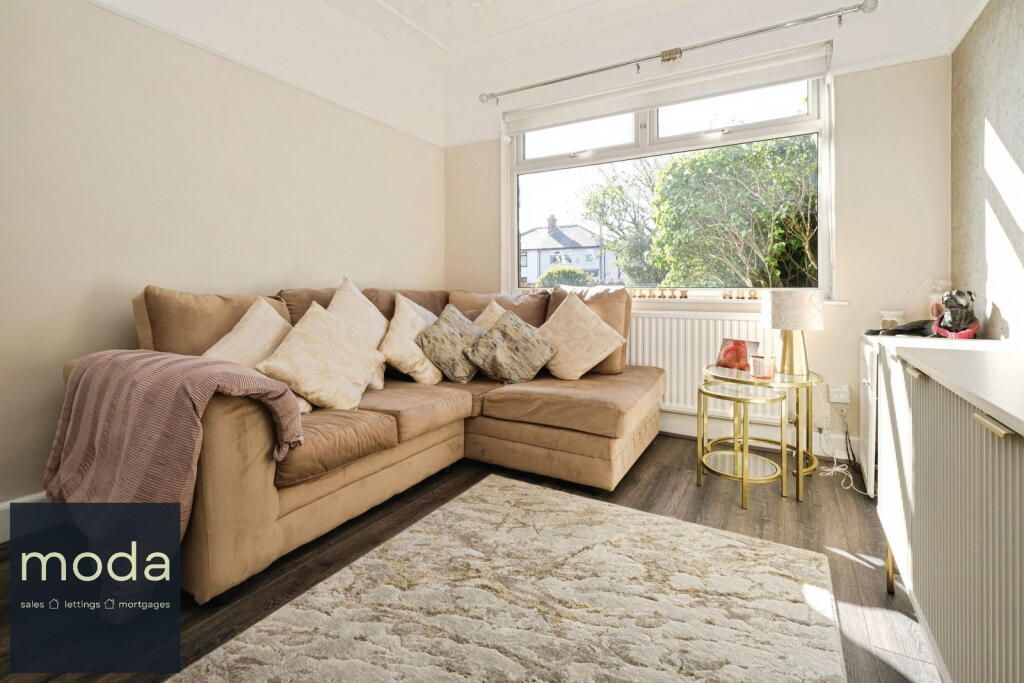 Living room with brown sectional sofa, window, and rug.