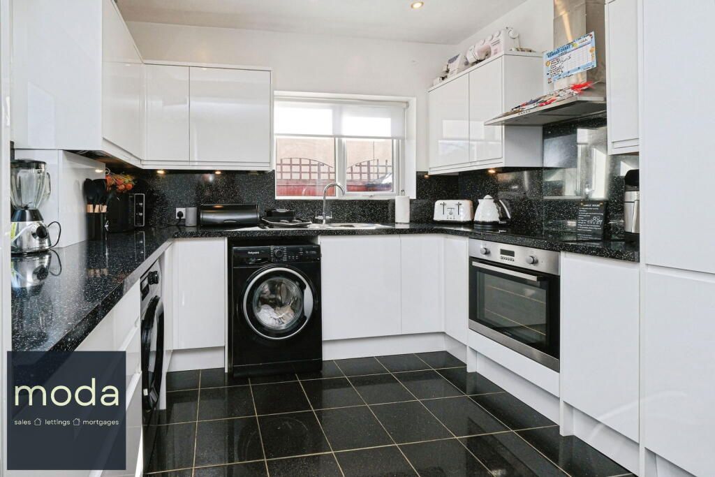 White kitchen with black countertops, appliances, and floor. Window at the center.