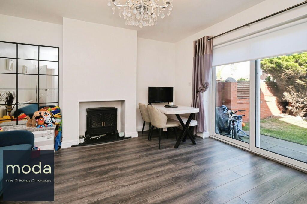 Living room with fireplace, dining table, large window, and glass wall. Grey floors.