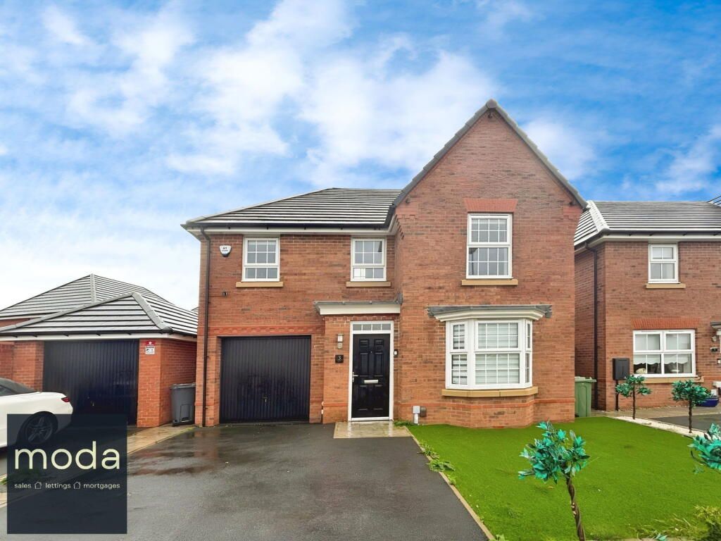 Brick house with a black garage door, lush green grass, and blue sky.
