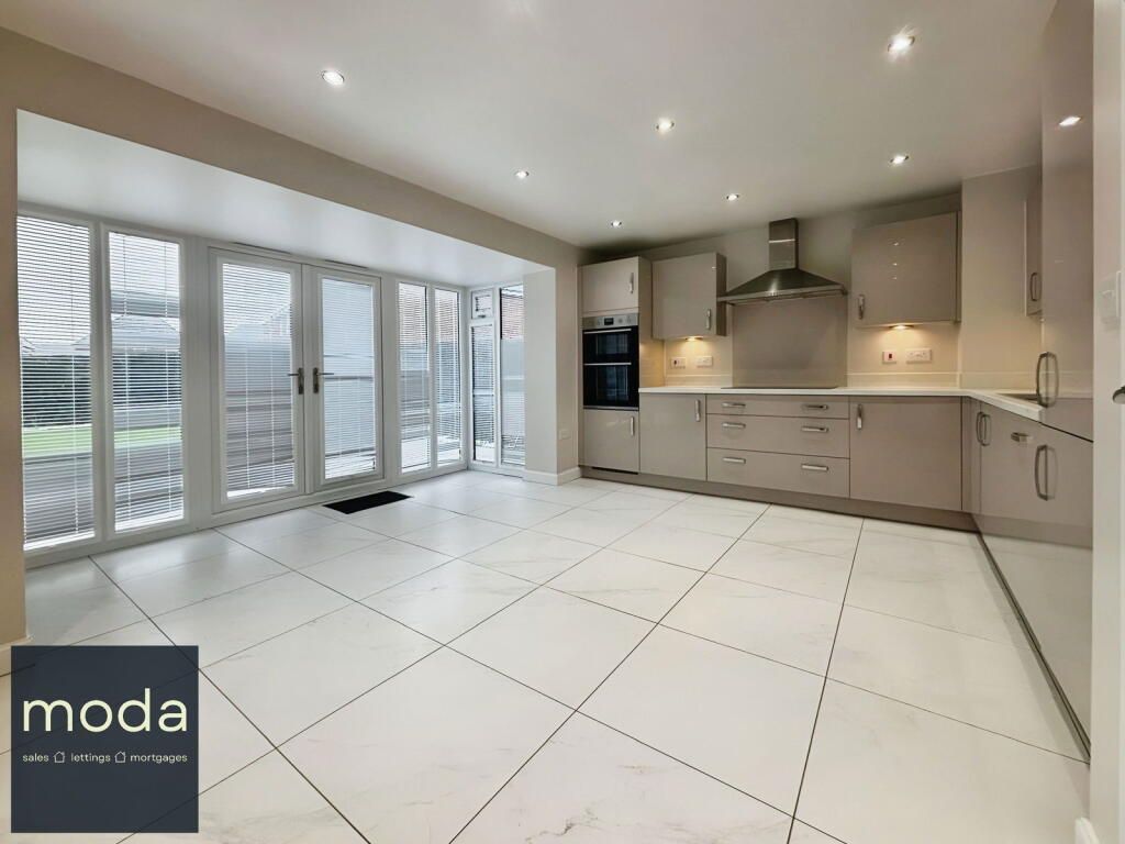 Modern kitchen with beige cabinets, white tiled floor, and large glass doors.