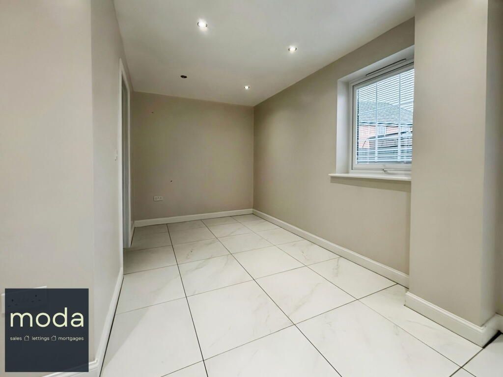 Empty room with white tile floors, beige walls, and a small window.