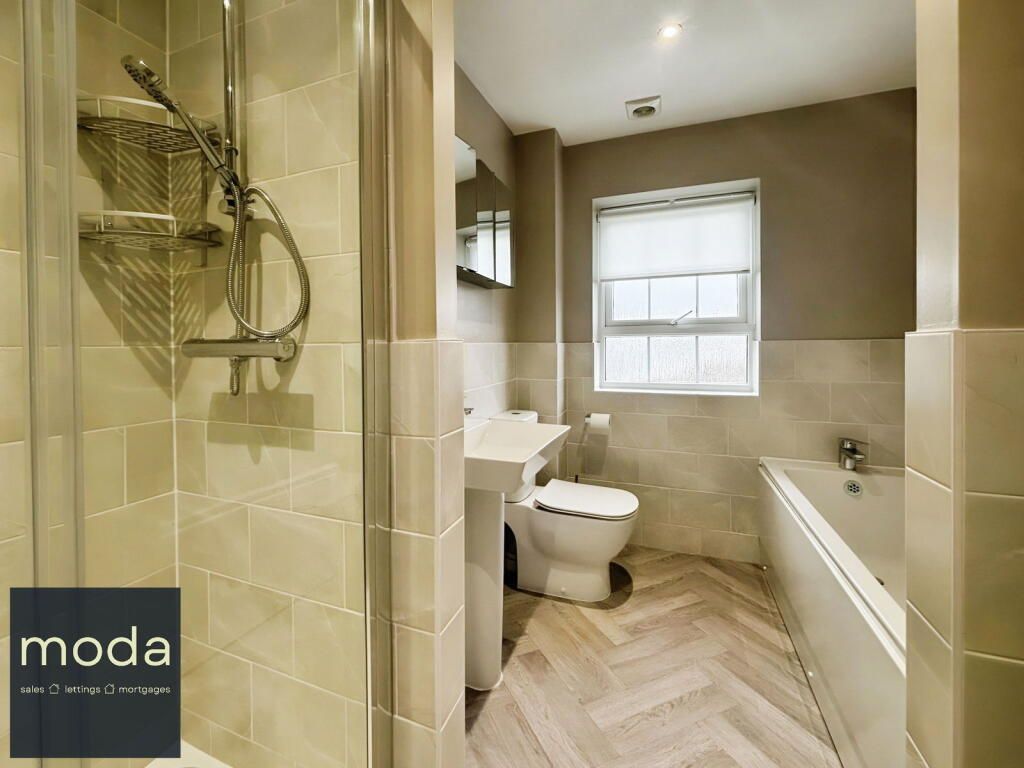 Bathroom with a shower, toilet, and tub. Light beige tiles and herringbone wood floors.