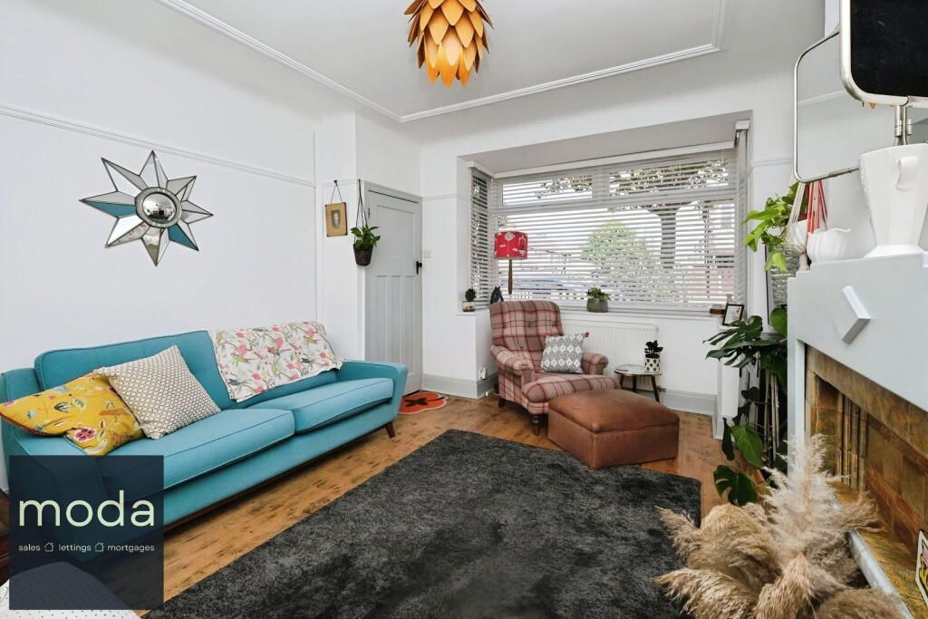Living room with turquoise couch, starburst mirror, and shaggy rug.