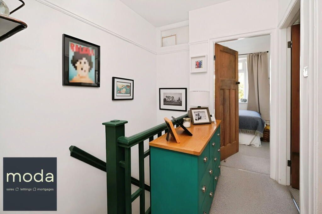 Hallway with a green dresser, black framed art, and a bedroom doorway.