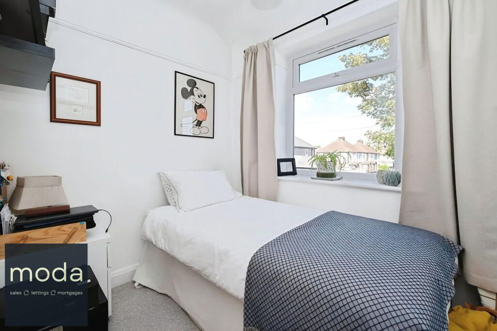 A small, white bedroom with a single bed near a window.