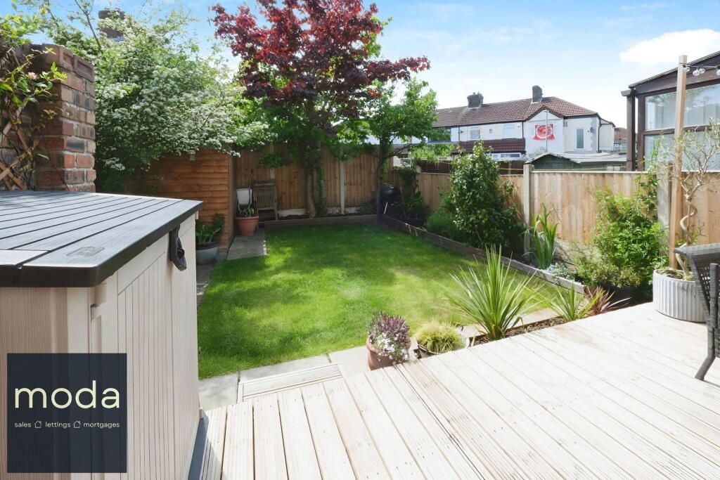 Backyard with wooden deck, green lawn, and surrounding wooden fence.