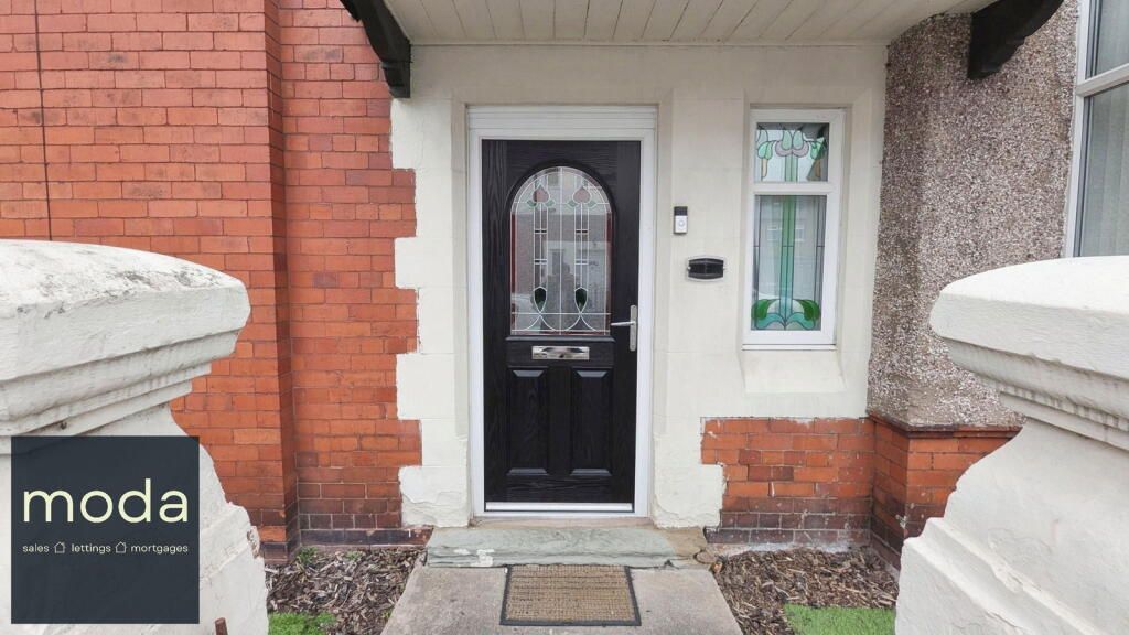 Black front door with glass panel, flanked by red brick and white trim.