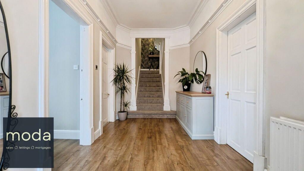Entryway with hardwood floors, doors, stairs, and a white console table with plants.