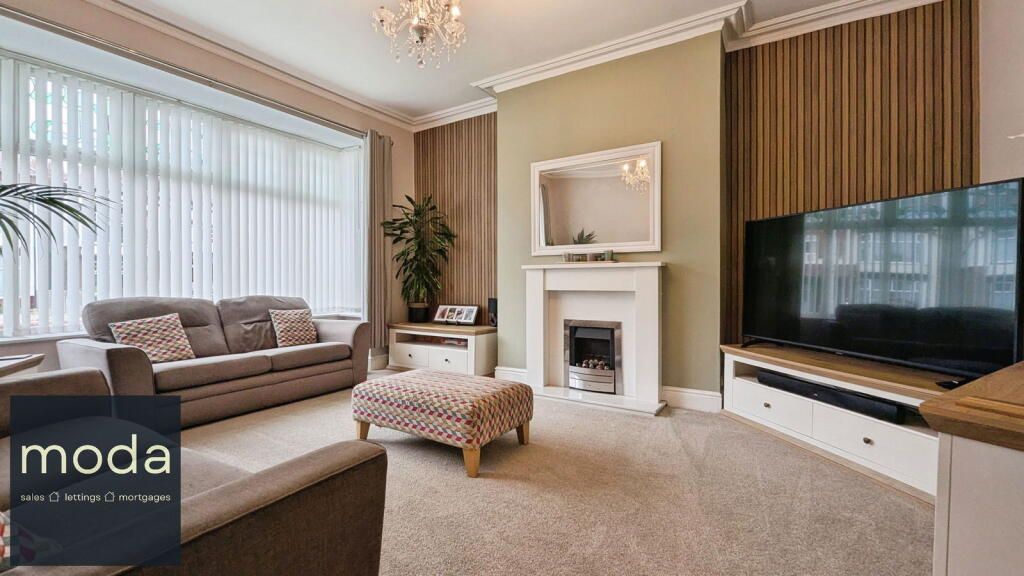 Living room with large windows, sofa, fireplace, and television. Neutral colors, with soft furnishings.
