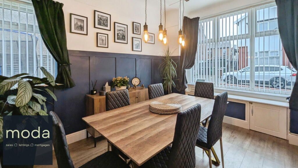Dining room with wooden table, six black chairs, dark blue wall, and windows.