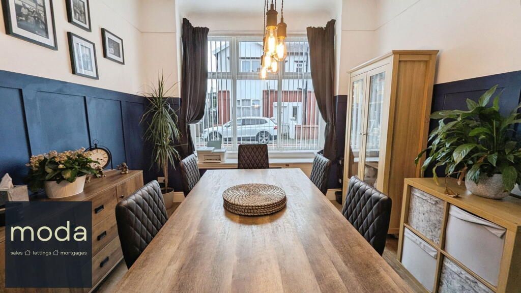 Dining room with wood table, blue paneling, wooden furniture, and window with view of street.
