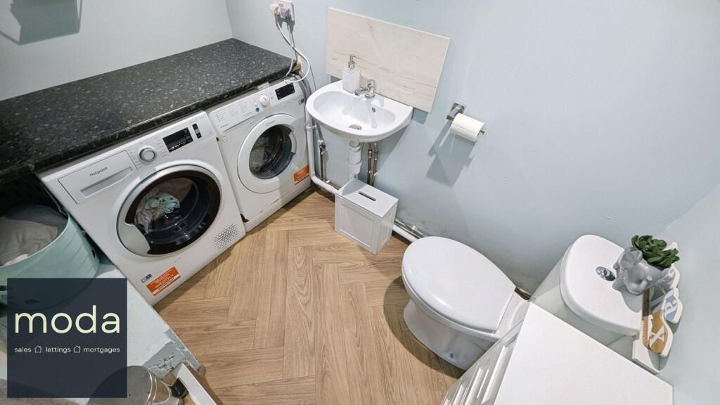Laundry room with washer, dryer, sink, toilet, and light blue walls.