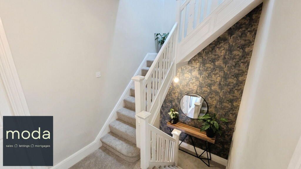 Staircase with white banisters, carpeted steps, and a dark patterned accent wall. 