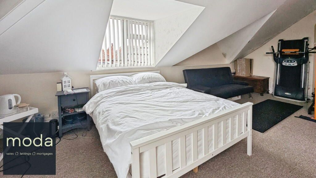 Bedroom with bed, futon, exercise machine, and slanted ceiling with window.
