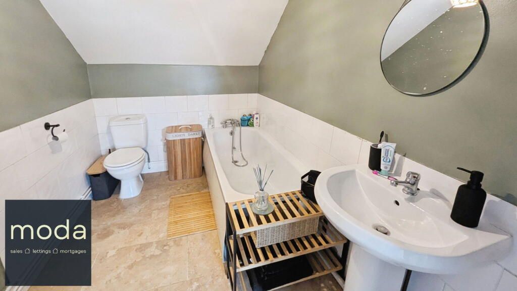 Bathroom with white and green walls, white fixtures, and wooden accents.