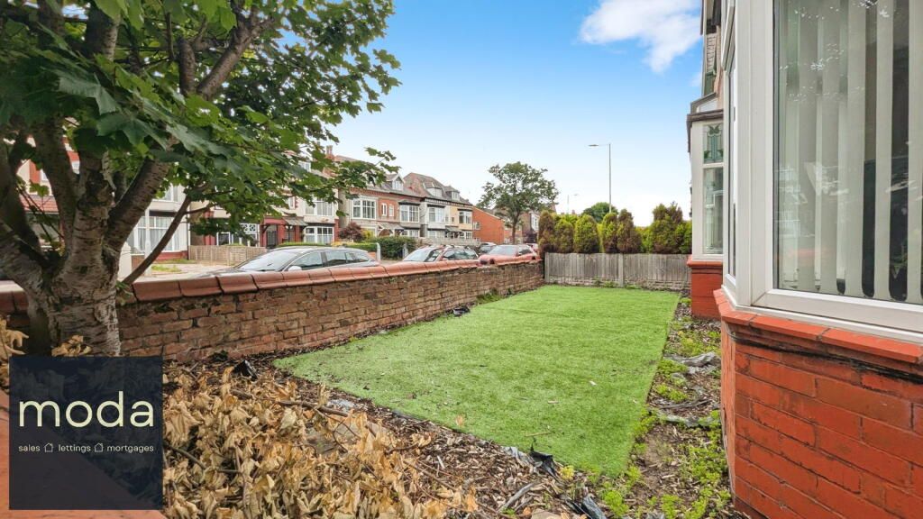 A small front yard with a brick wall and grass. A tree and house with bay windows are visible.