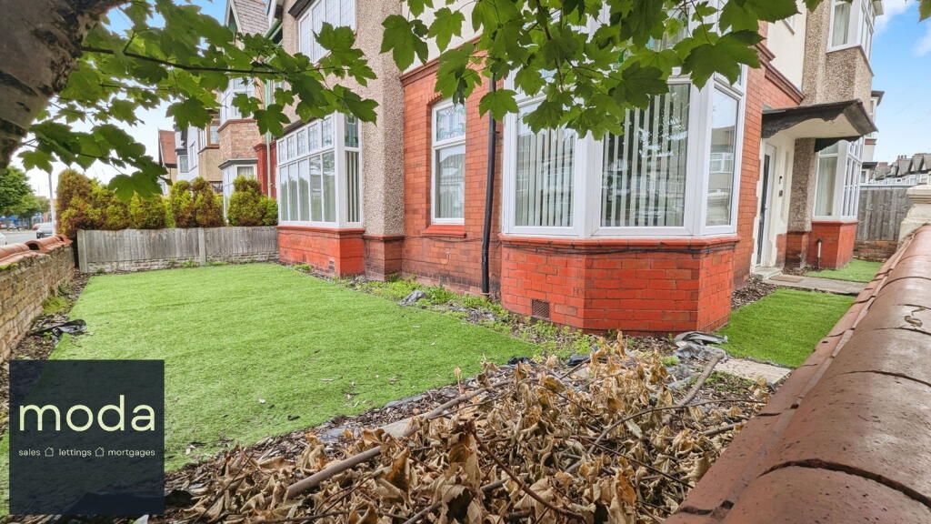 Exterior view of a red brick house with a front yard, green grass, and tree.