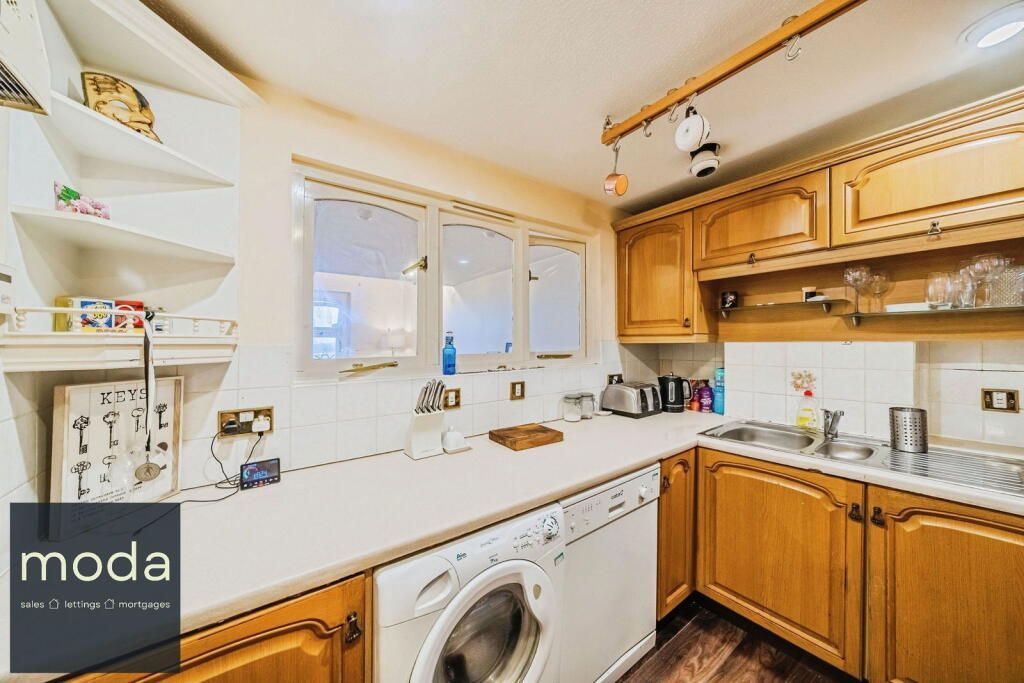 Kitchen with wooden cabinets, white countertops, and a washing machine.