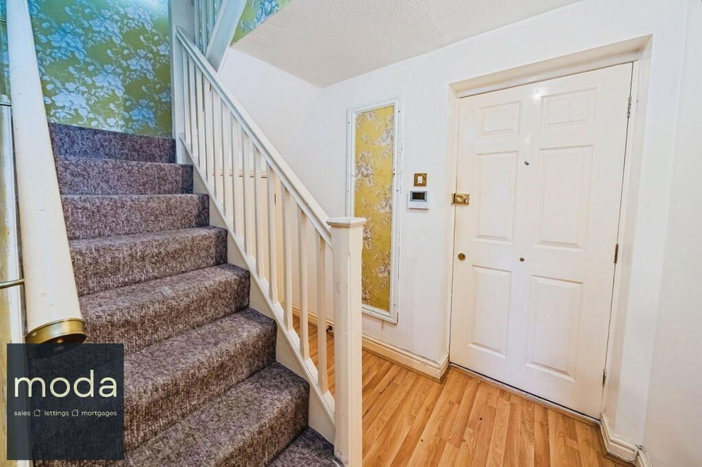 Staircase with carpeted steps, white railing, door and wood floor. Wallpaper accent wall.