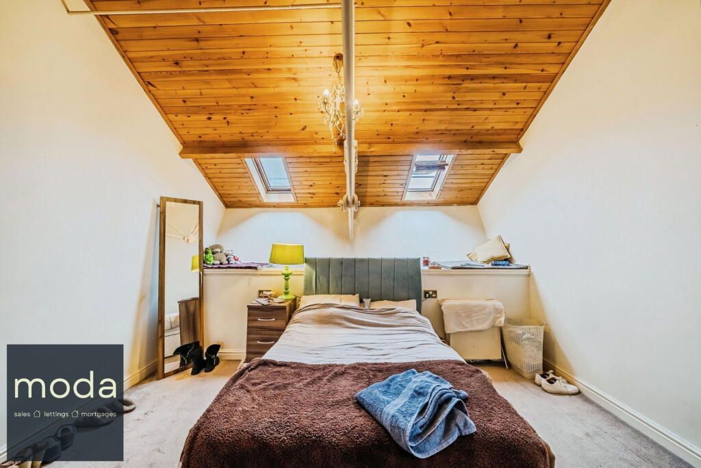 Bedroom with wooden ceiling, skylights, bed, and side tables.