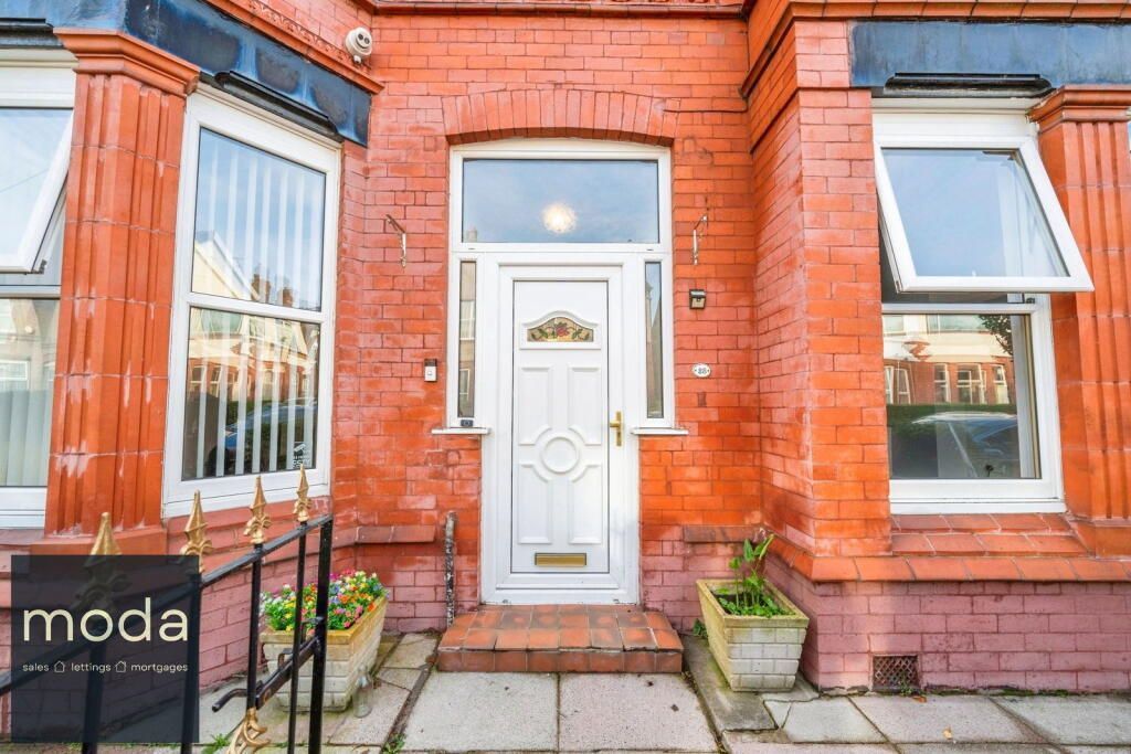 Red brick house with white door, side windows open, front yard with pots, and gold sign.