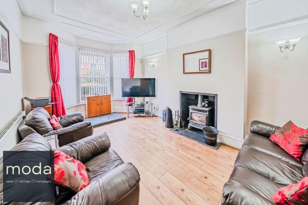 Living room with brown leather sofas, TV, fireplace, red curtains.