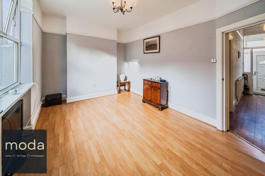 Empty living room with hardwood floor, gray walls, and a brown cabinet.