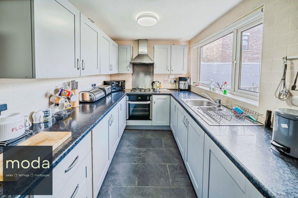 Modern kitchen with white cabinets, dark countertops, and stainless steel appliances.